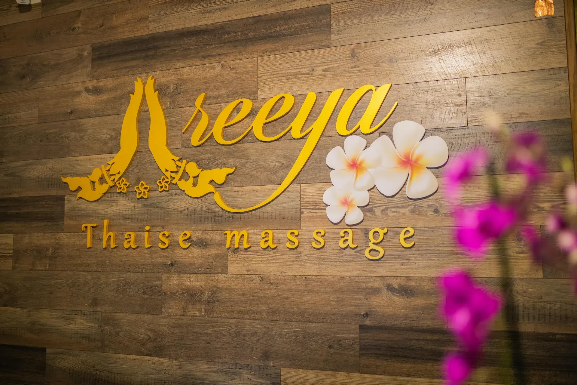 Goudkleurig logo op de muur bij de balie van Areeya Thaise Massage in Rotterdam